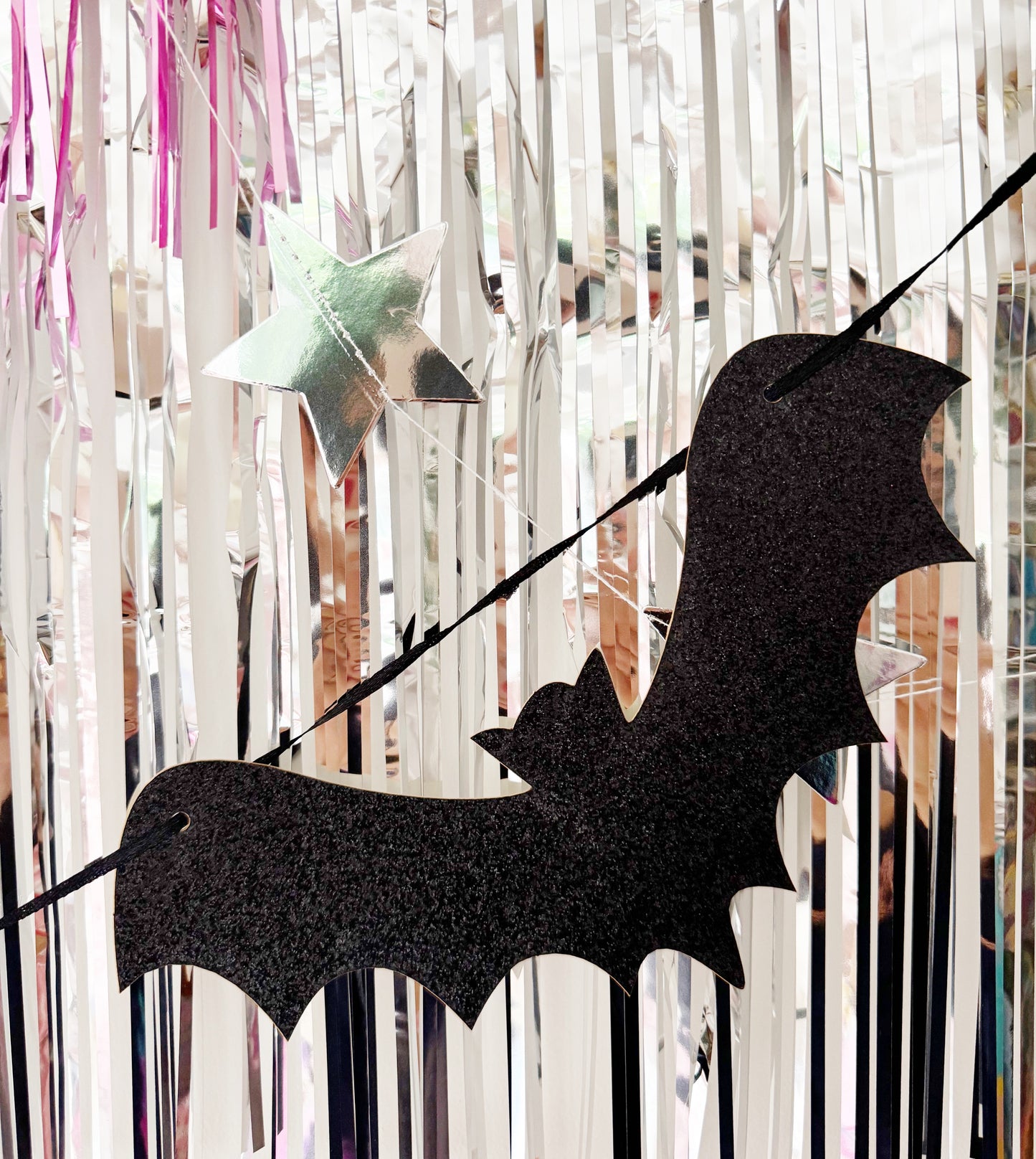 Black bat-shaped decoration against a colorful fringe curtain