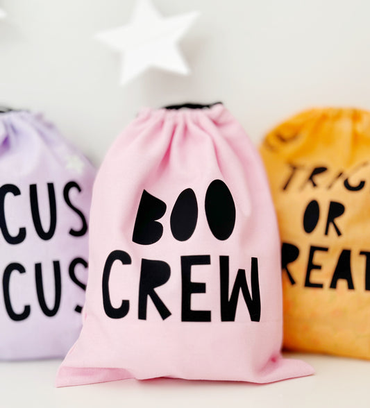 Pink drawstring bag with 'BOO CREW' text, surrounded by other Halloween-themed bags.