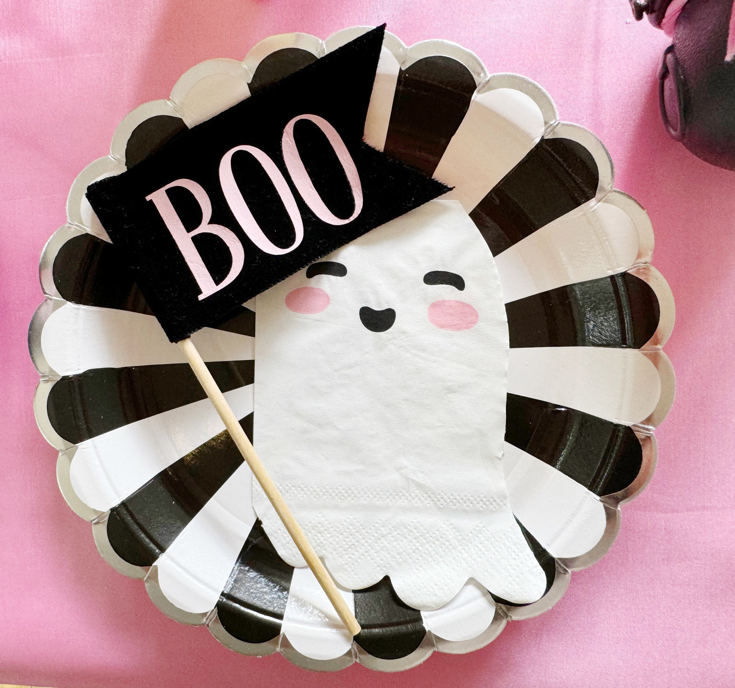 Halloween-themed paper plate with ghost design and 'BOO' banner on pink background