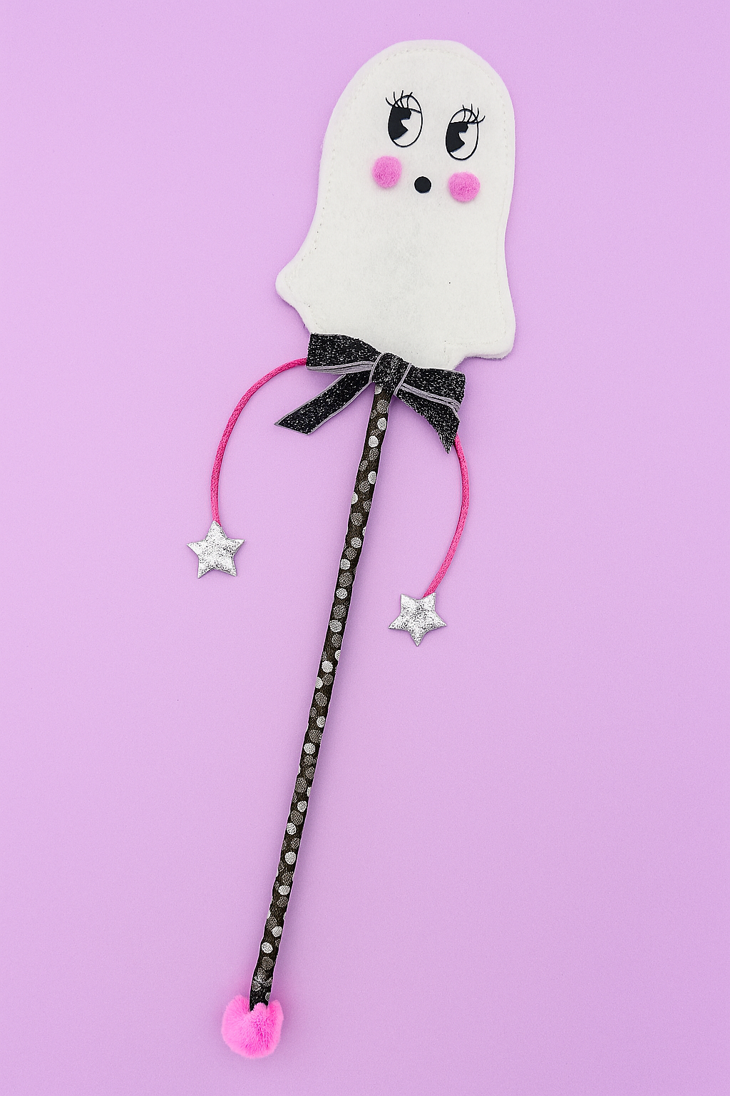 Ghost-shaped wand with a pink ribbon on a purple background
