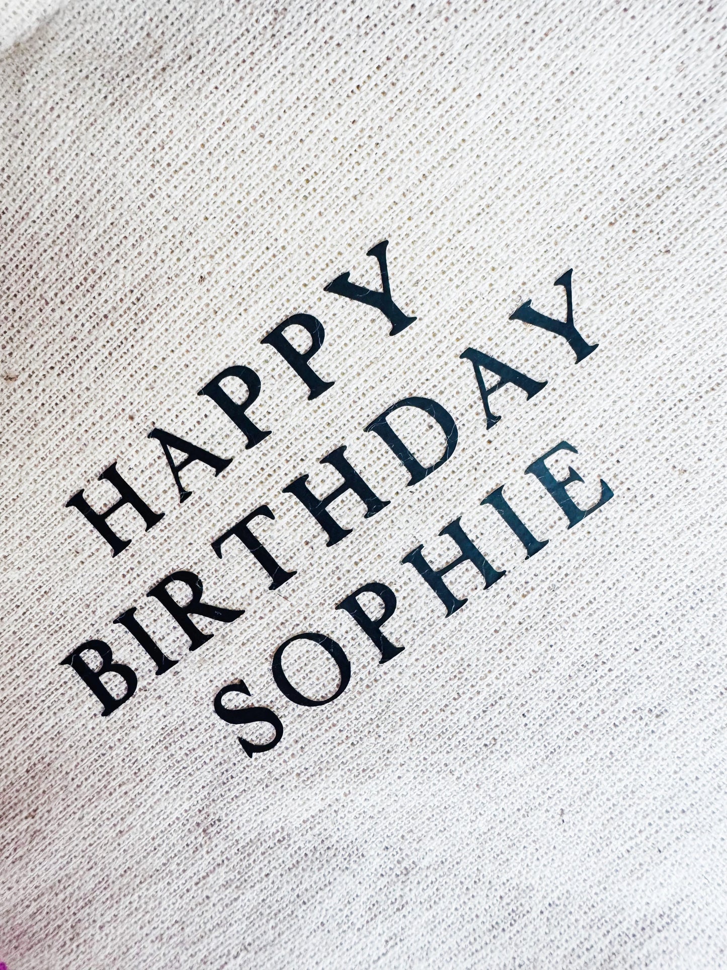 Text 'Happy Birthday Sophie' on a textured fabric background