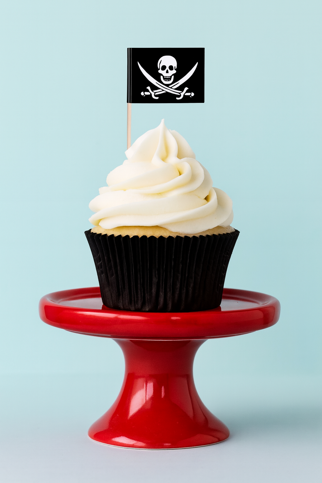 Cupcake with white frosting and a black pirate flag on a red stand against a light blue background
