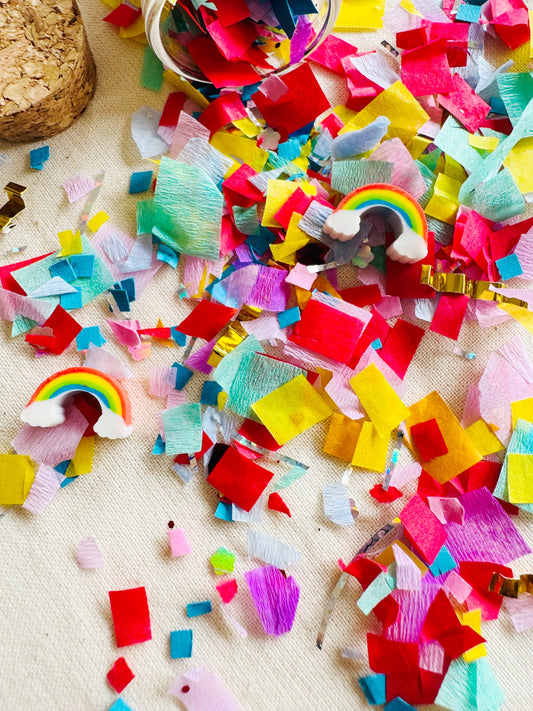 Colorful confetti with rainbows and unicorns on a beige surface