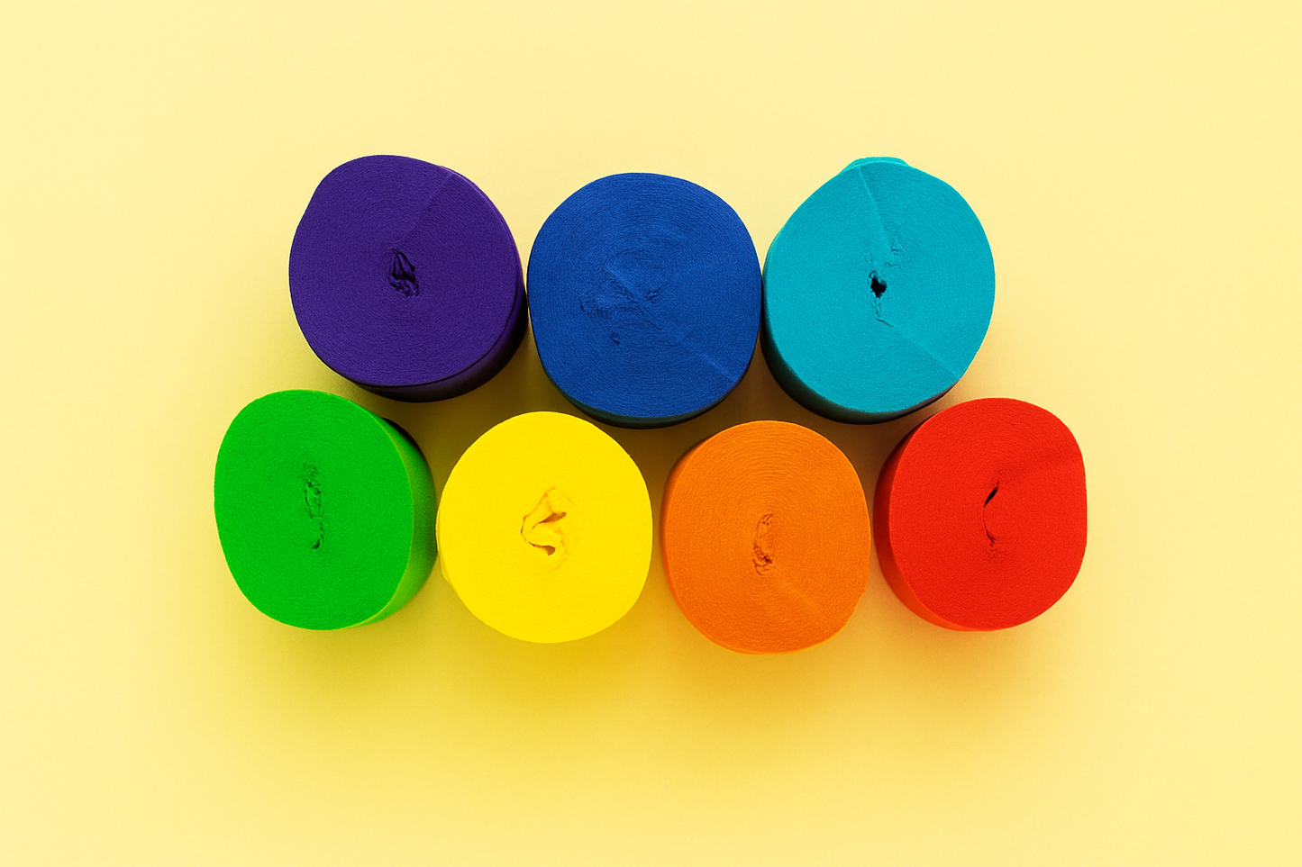 Seven colourful rolls of paper streamers in a rainbow pattern on a yellow background