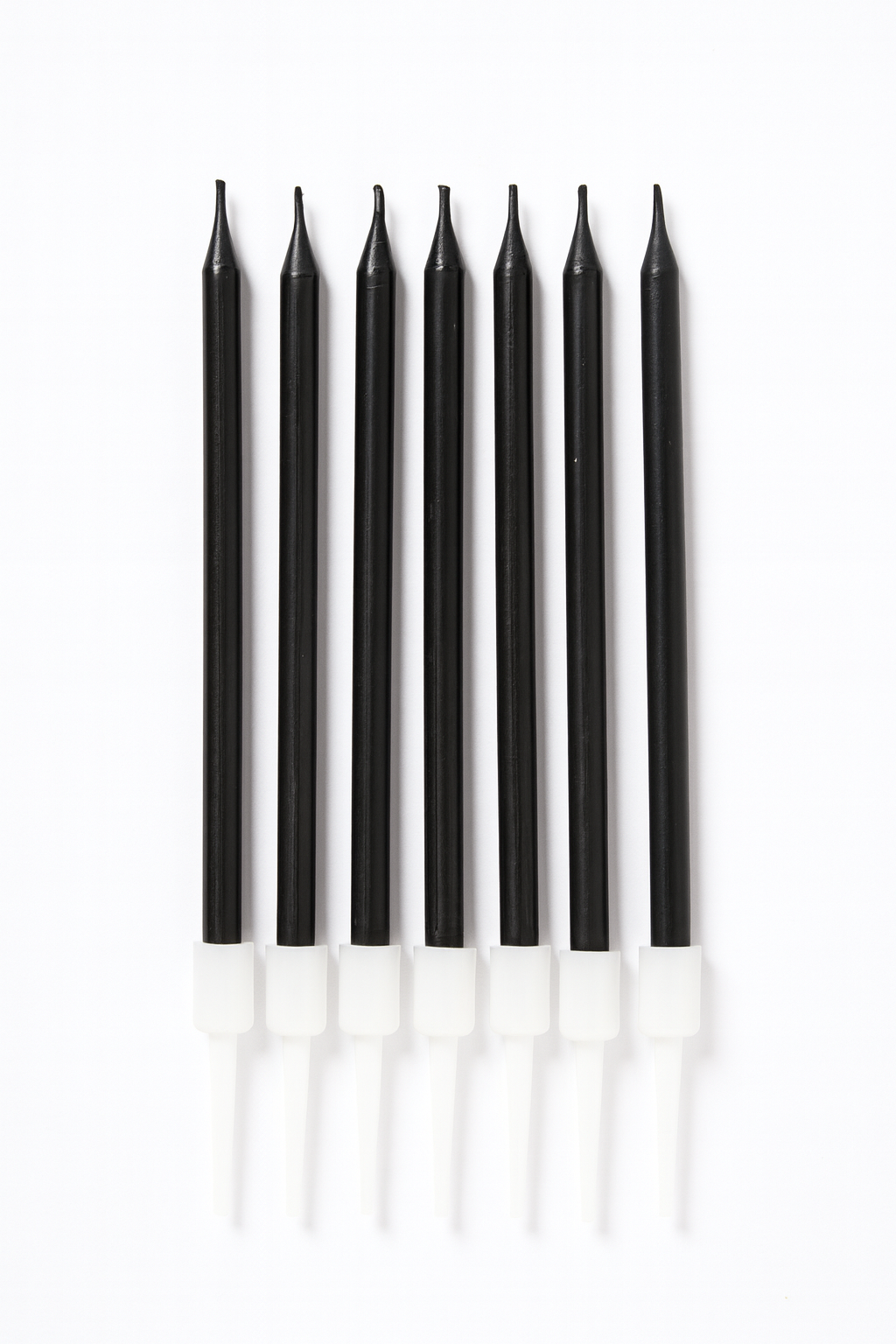 Set of black candles with white bases on a white background