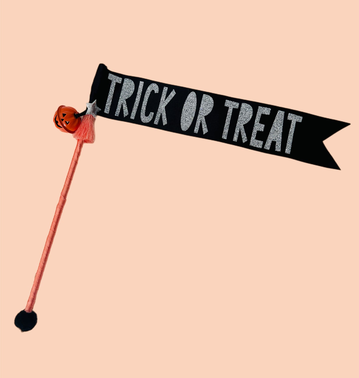 Halloween-themed stick with 'Trick or Treat' banner and pumpkin decoration on a beige background