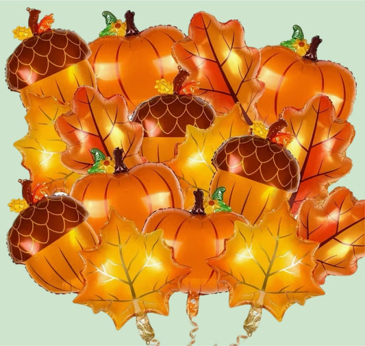 Decorative balloons shaped like pumpkins, leaves, and acorns on a light green background