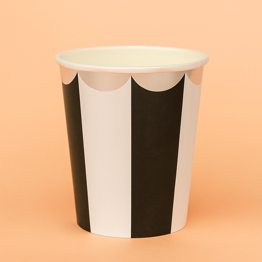 Paper cup with black and white striped design on a peach background