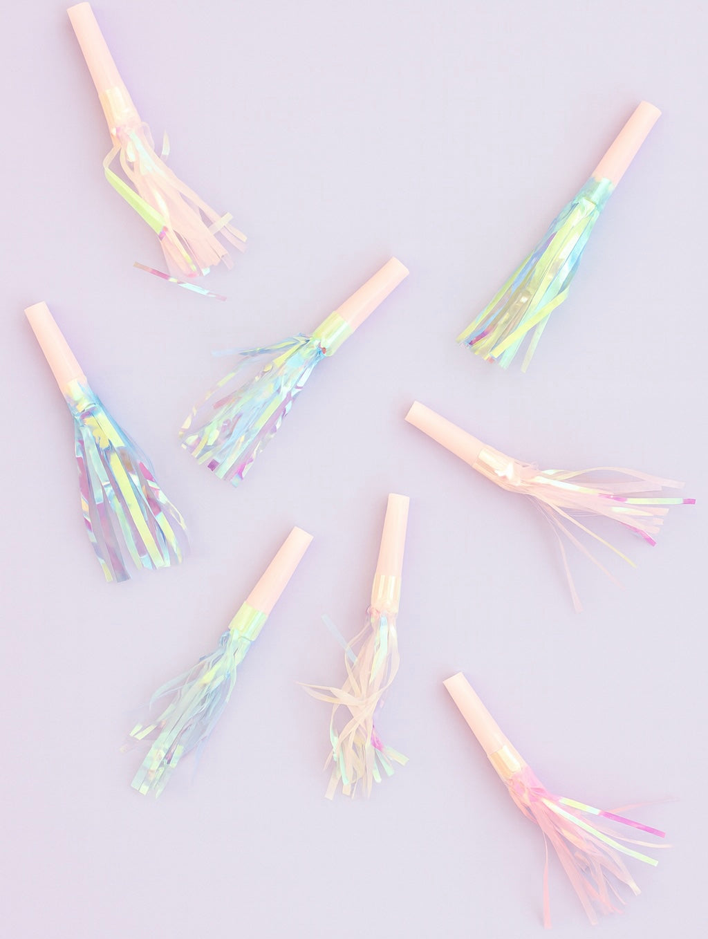 Iridescent party noisemakers on a light purple background