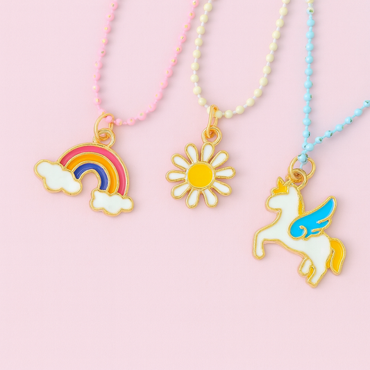 Three colorful necklaces with rainbow, sun, and unicorn charms on a pink background