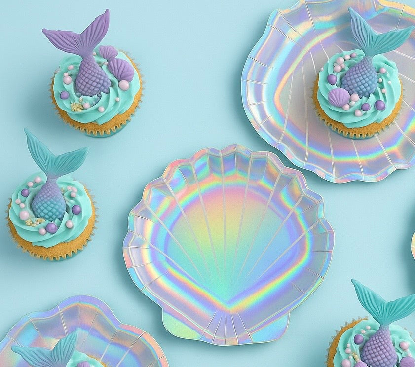 Cupcakes with mermaid tails on a blue background with iridescent shell-shaped plates.