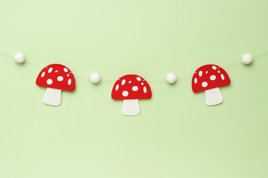 Decorative string of red and white polka dot felt toadstools on a light green background 