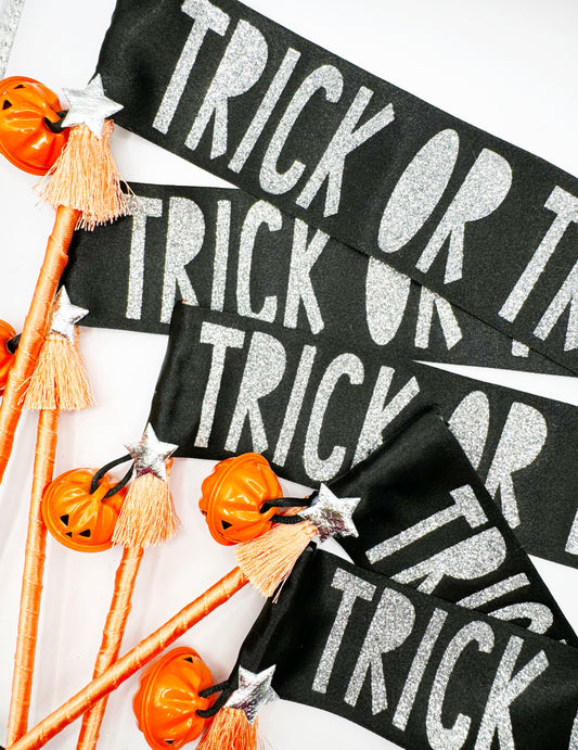 Black and white 'Trick or Treat' banner wand with Halloween decorations on a white background