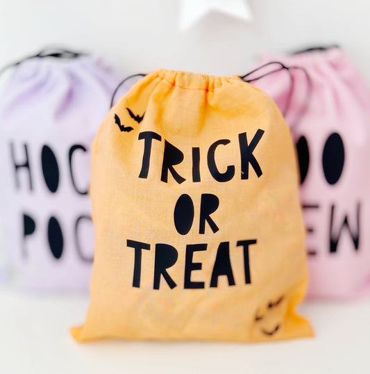 Yellow drawstring bag with 'Trick or Treat' text, surrounded by other Halloween-themed bags.
